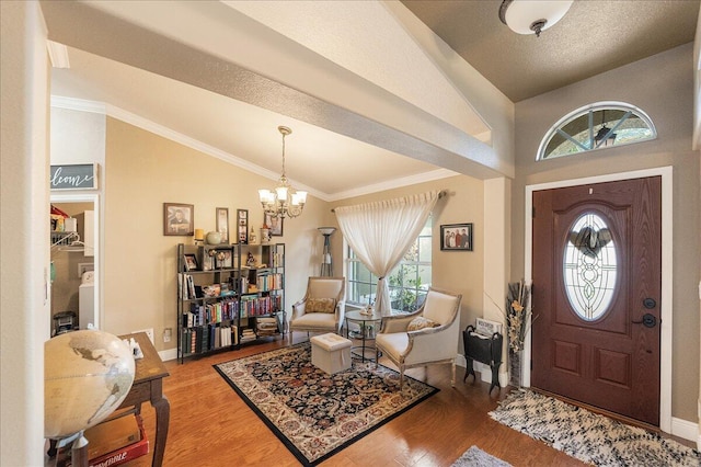 foyer featuring a wealth of natural light, lofted ceiling, hardwood / wood-style floors, and a chandelier