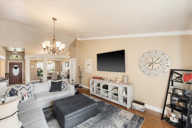 living room featuring a notable chandelier, vaulted ceiling, hardwood / wood-style floors, and ornamental molding