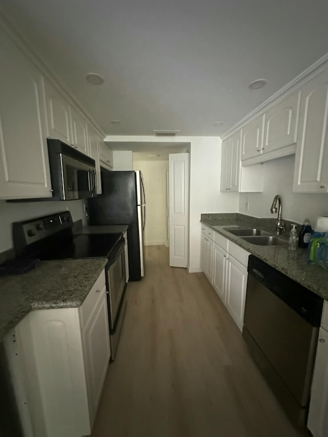 kitchen featuring sink, appliances with stainless steel finishes, white cabinets, dark stone counters, and light wood-type flooring