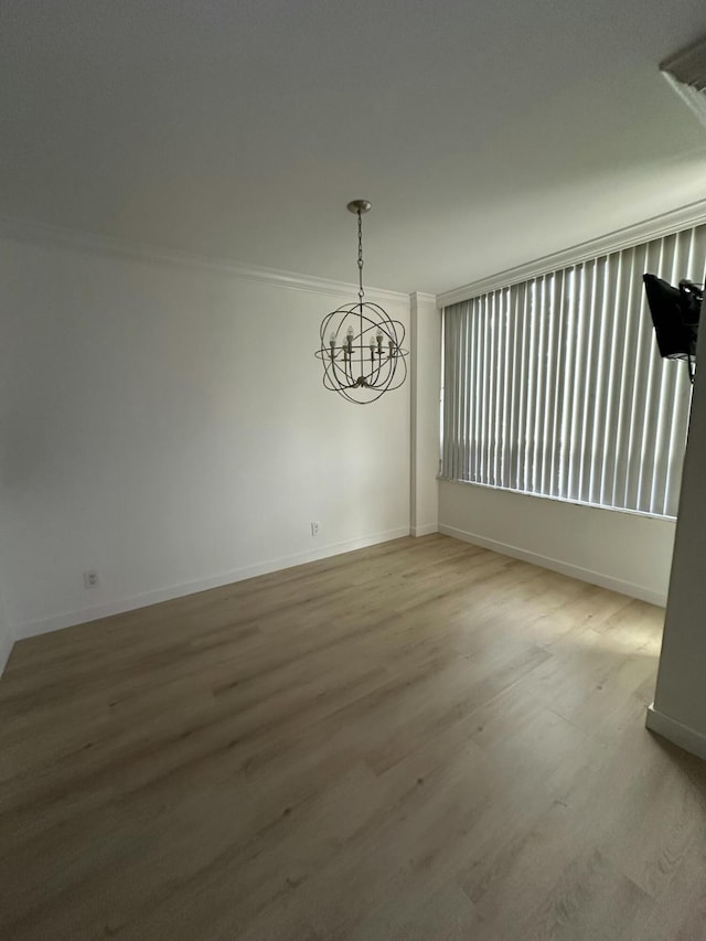 empty room with wood-type flooring, a notable chandelier, and crown molding