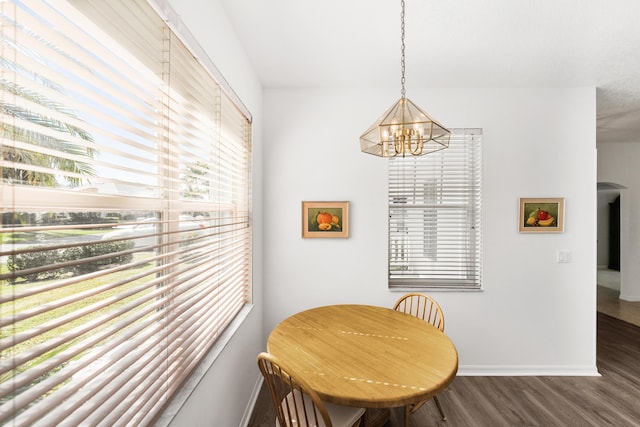 dining area with a healthy amount of sunlight, dark hardwood / wood-style floors, and a chandelier