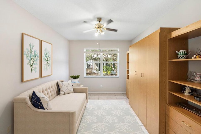 sitting room featuring light tile patterned floors, a textured ceiling, baseboards, and a ceiling fan