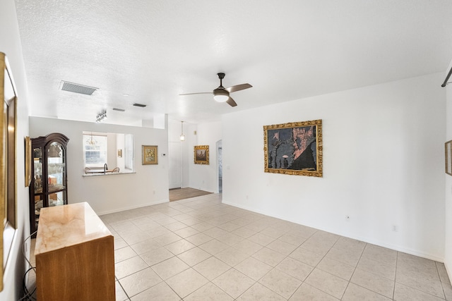 unfurnished living room featuring ceiling fan, a textured ceiling, and light tile patterned floors