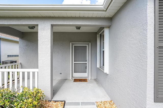 property entrance with central AC and stucco siding