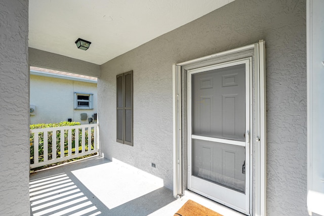 doorway to property featuring a porch and stucco siding