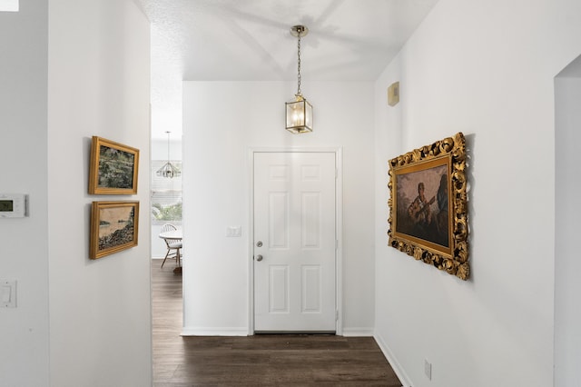 foyer entrance with dark wood-style floors and baseboards