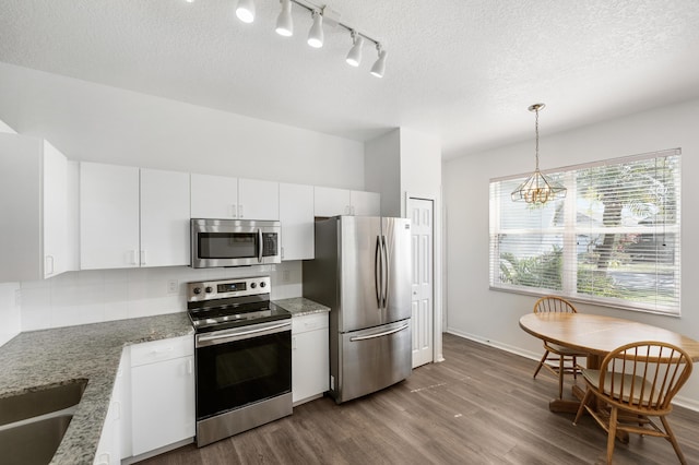 kitchen featuring stainless steel appliances, dark wood-type flooring, white cabinetry, decorative backsplash, and decorative light fixtures