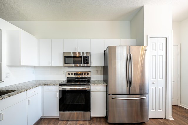 kitchen with white cabinets, dark wood-style floors, stainless steel appliances, and backsplash