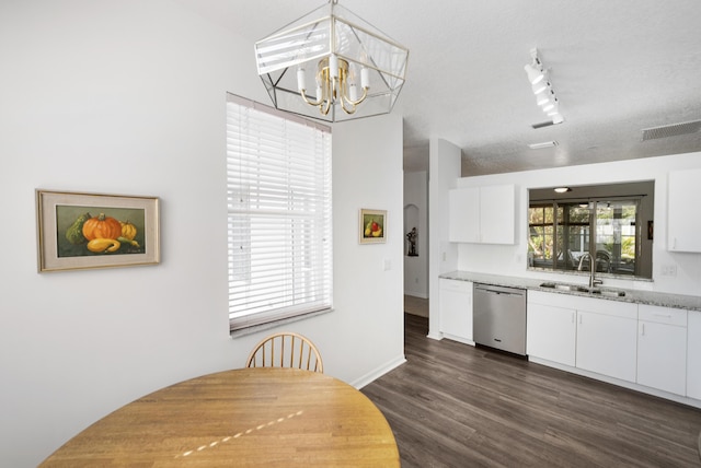 dining room with rail lighting, sink, dark wood-type flooring, and an inviting chandelier