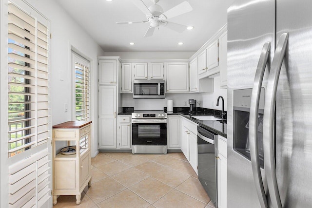 kitchen with appliances with stainless steel finishes, white cabinetry, sink, light tile patterned floors, and ceiling fan