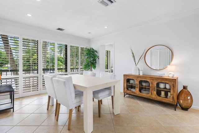 tiled dining space featuring ornamental molding and a textured ceiling