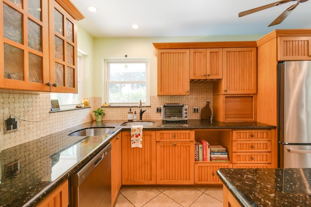 kitchen with a toaster, stainless steel appliances, backsplash, light tile patterned flooring, and a sink