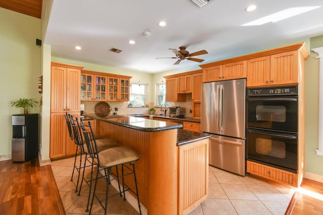 kitchen featuring freestanding refrigerator, dobule oven black, visible vents, and light tile patterned flooring