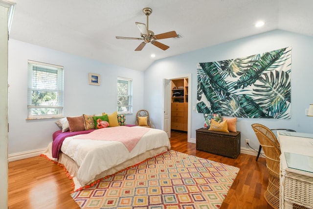 bedroom with lofted ceiling, a spacious closet, baseboards, and wood finished floors