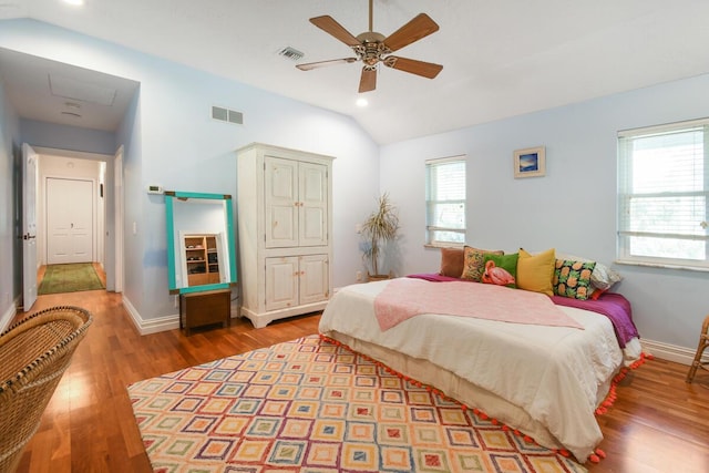 bedroom featuring light wood-style floors, visible vents, vaulted ceiling, and baseboards