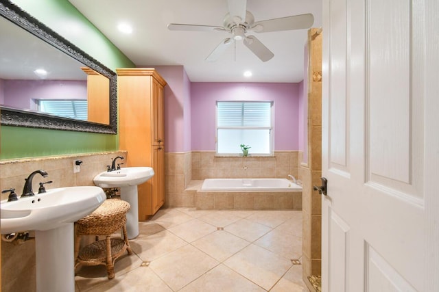 bathroom with a ceiling fan, a bath, a wainscoted wall, tile patterned floors, and tile walls