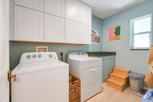 washroom featuring washer and dryer, cabinet space, and light tile patterned flooring