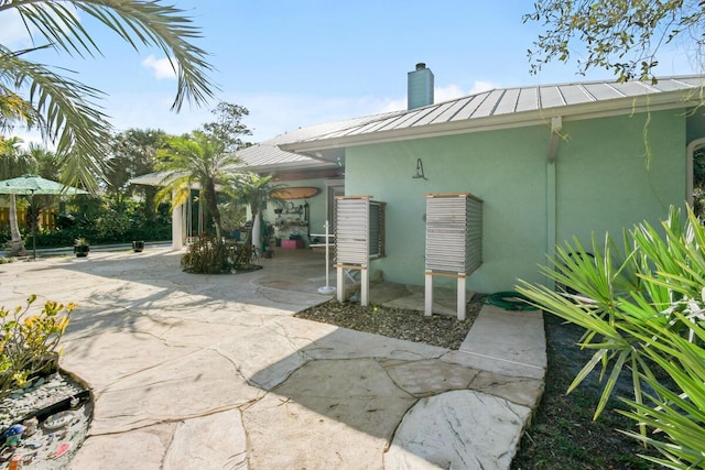 exterior space featuring metal roof, a patio, a standing seam roof, and stucco siding