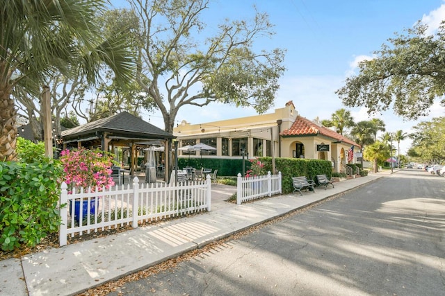 view of front of property with stucco siding, a fenced front yard, a tile roof, and a gazebo