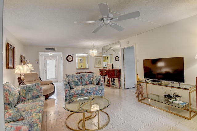 living room with ceiling fan with notable chandelier and a textured ceiling