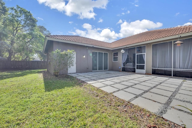 back of house with a patio area, a sunroom, and a lawn