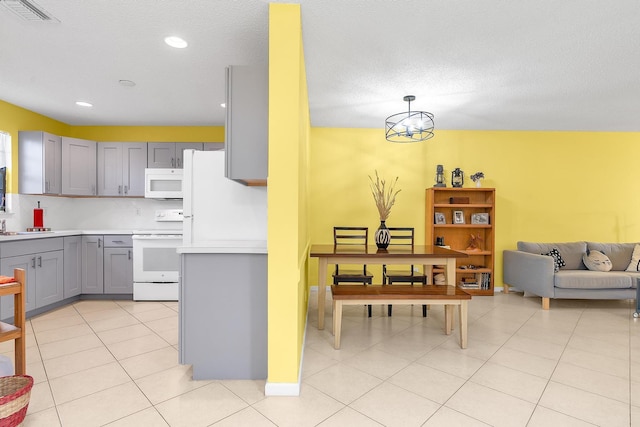 kitchen featuring gray cabinetry, tasteful backsplash, hanging light fixtures, light tile patterned floors, and white appliances