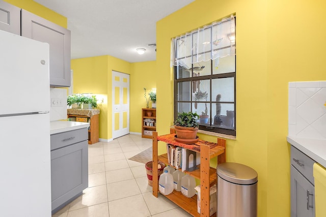 kitchen featuring light tile patterned flooring, white fridge, and gray cabinetry