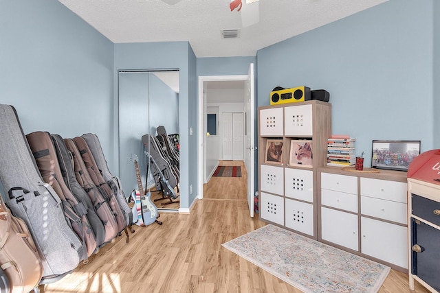 interior space with ceiling fan, a textured ceiling, and light wood-type flooring