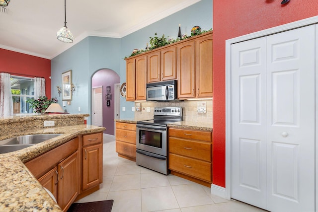 kitchen with arched walkways, light tile patterned floors, stainless steel appliances, decorative backsplash, and crown molding