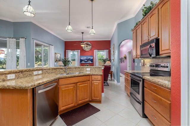 kitchen featuring arched walkways, appliances with stainless steel finishes, a sink, and light stone countertops