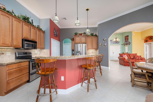 kitchen featuring light stone countertops, appliances with stainless steel finishes, arched walkways, and a breakfast bar area