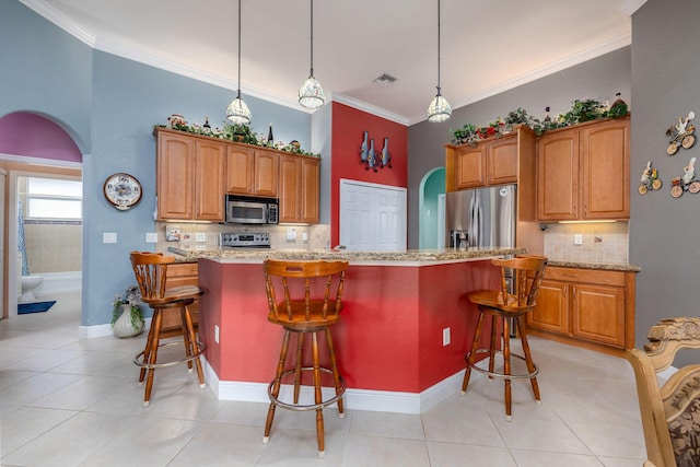 kitchen with light stone countertops, appliances with stainless steel finishes, arched walkways, and ornamental molding