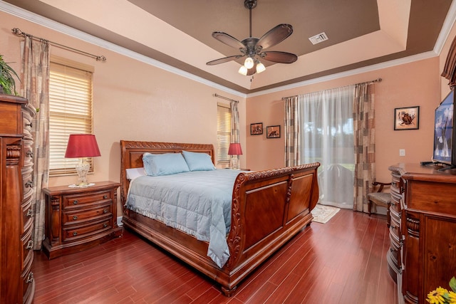 bedroom featuring ornamental molding, a raised ceiling, visible vents, and dark wood-style flooring