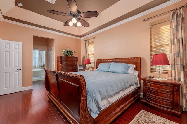 bedroom featuring dark wood-type flooring, a tray ceiling, ornamental molding, and baseboards