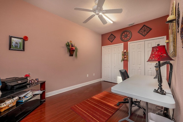 office space with dark wood-style floors, visible vents, ceiling fan, and baseboards