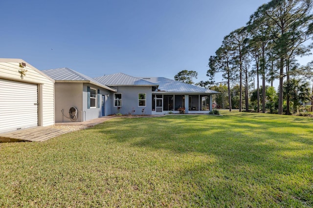 back of property featuring metal roof, a lawn, a sunroom, and stucco siding