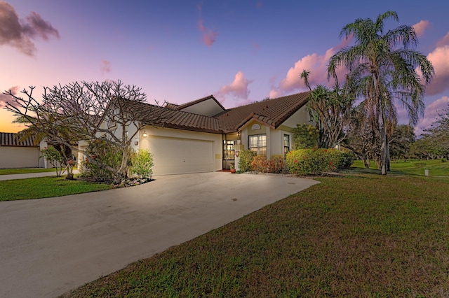 mediterranean / spanish-style house featuring a garage and a lawn