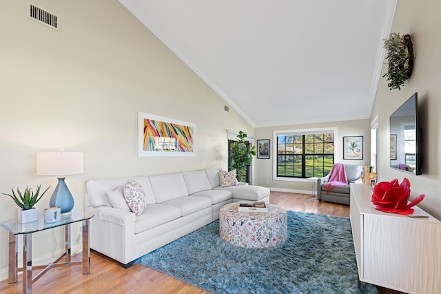 living room with hardwood / wood-style flooring, ornamental molding, and high vaulted ceiling