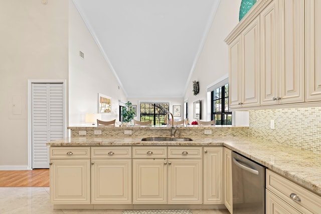 kitchen featuring lofted ceiling, sink, stainless steel dishwasher, and cream cabinetry