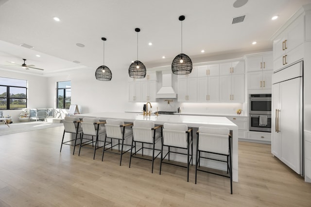 kitchen with a large island, light countertops, stainless steel double oven, open floor plan, and premium range hood