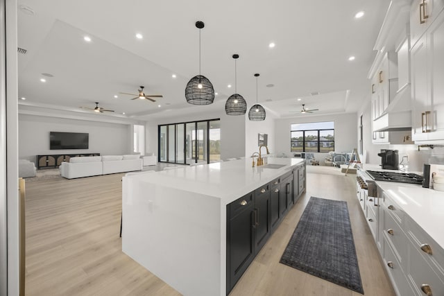 kitchen with a spacious island, light countertops, hanging light fixtures, open floor plan, and white cabinets