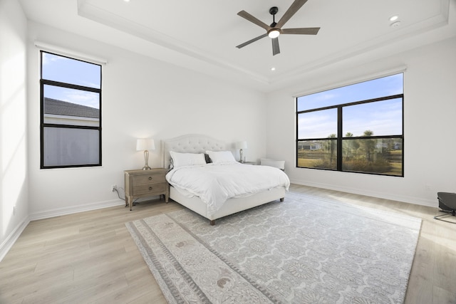 bedroom featuring baseboards, a raised ceiling, a ceiling fan, light wood-type flooring, and recessed lighting