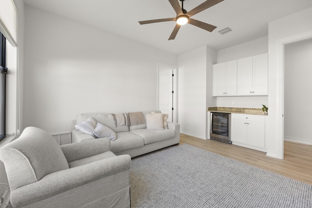 living room featuring a dry bar, light wood finished floors, beverage cooler, and visible vents