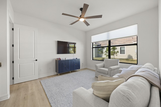 living area featuring light wood-style flooring, baseboards, and a ceiling fan