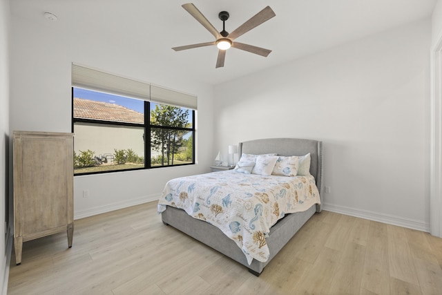 bedroom with light wood-style floors, ceiling fan, and baseboards