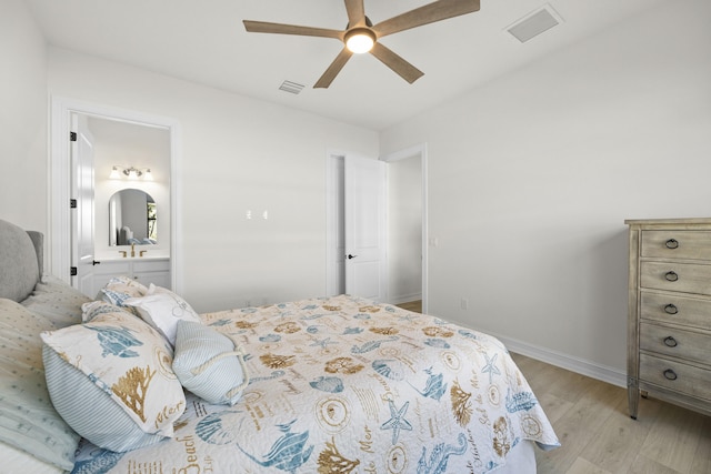 bedroom with baseboards, visible vents, ensuite bath, and light wood finished floors