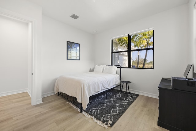 bedroom with light wood-style floors, baseboards, and visible vents