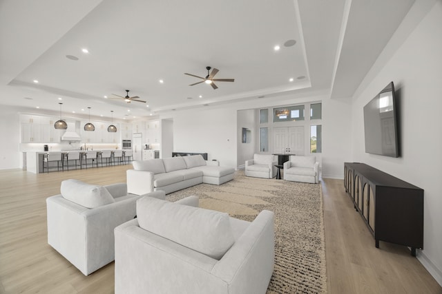 living area featuring light wood-style flooring, a raised ceiling, and recessed lighting