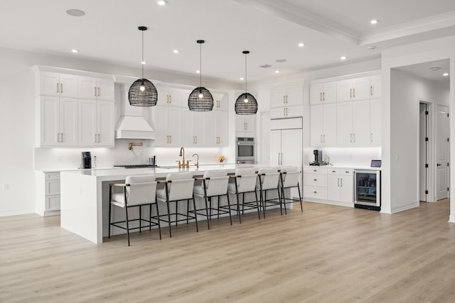 kitchen featuring a large island, a breakfast bar area, light countertops, white cabinetry, and beverage cooler