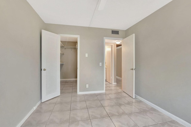 unfurnished bedroom featuring a walk in closet, a closet, and light tile patterned flooring